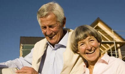 Älteres Paar, das Plan vor teilweise gebautem Haus hält