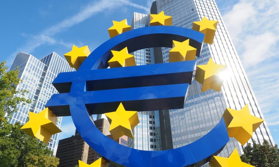 Ein blaues Eurozeichen umrahmt von 12 gelben Sternen vor Hochhäusern
